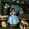 child, girl, blue_dress, mushroom, flowers, greenery, nature, fantasy, portrait, indoor, decor, plant, tree_stump, smile, playful, cute, dress, sitting, whimsical, fairy_tale