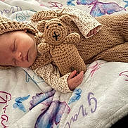 Gracielynn joined the competition — help win amazing prizes! baby, bedtime, blanket, butterfly_pattern, child, cozy, crocheted_toy, cute, handmade, indoors, infant, knitted_clothing, peaceful, portrait, resting, sleeping, small_hands, soft_texture, teddy_bear, warm