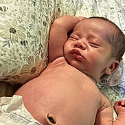 Joseph is registered to the contest to win money with this photo: newborn, baby, sleeping, pillow, floral_pattern, infant, skin, arm, peaceful, resting, closeup, cute, indoors, blanket, face, head, relaxation, child, human, portrait