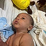 Joseph is registered to the contest to win money with this photo: baby, infant, face, skin, blanket, plush_toy, pineapple_toy, bed, quilt, soft, child, cute, indoors, expression, gaze, comfort, sleepwear, newborn, resting, closeup