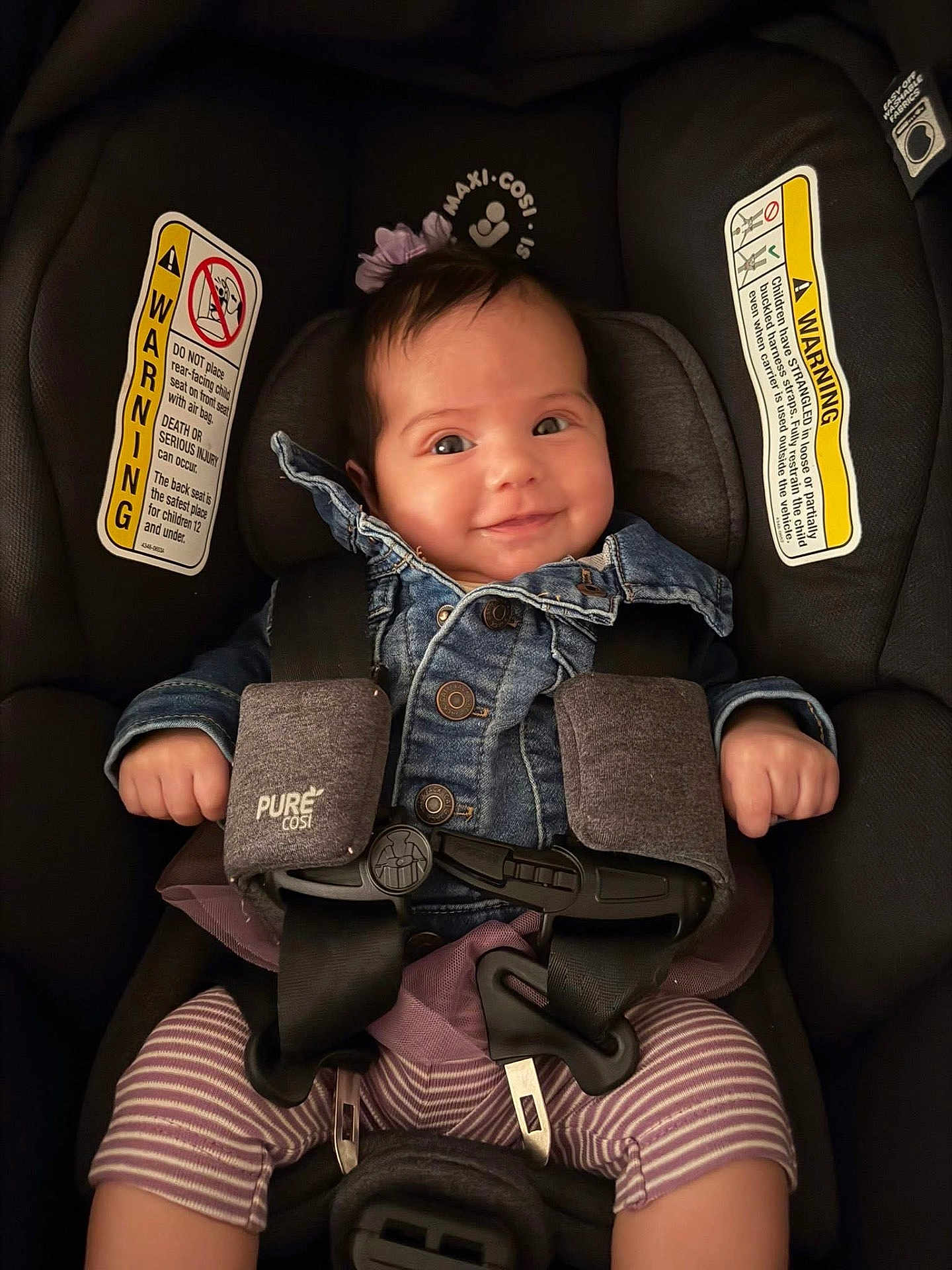 Araceli is registered to the contest to win money with this photo: baby, car_seat, denim_jacket, smile, child, straps, purple_bow, infant, clothing, seatbelt, cute, happy, indoors, safety, toddler, face, person, striped_pants, button, headwear