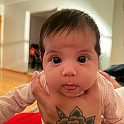 Araceli joined the competition — help win amazing prizes! baby, infant, tattoo, hand, face, tongue, curious, indoor, person, child, skin, clothing, long_sleeve, portrait, expression, holding, young, cute, human, closeup