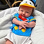 Kurt participe au concours pour gagner de l'argent avec cette photo : baby, infant, child, blue_shirt, donald_duck_hat, red_bow, white_blanket, cute, smiling, portrait, indoors, soft_texture, crossed_hands, clothing, headwear, person, cute_expression, relaxed, baby_girl, baby_boy