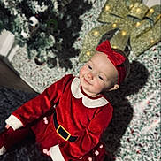 Ivy-Mai joined the competition — help win amazing prizes! baby, child, red_clothing, headband, bow, christmas_tree, holiday, carpet, indoor, festive, smile, portrait, decorations, lights, toddler, sitting, cozy, seasonal, cute, happy