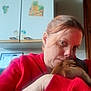 woman, dog, indoor, selfie, red_hoodie, brown_dog, affection, kitchen, cabinet, fruit_stickers, close_up, casual, portrait, human, pet, love, cuddle, warmth, face, hand