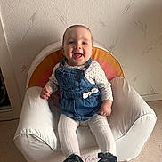 Elya participe au concours pour gagner de l'argent avec cette photo : baby, child, smiling, denim_dress, white_tights, black_shoes, armchair, rainbow_pattern, indoor, happy, cute, sitting, person, face, head, furniture, floor, wall, home, cozy