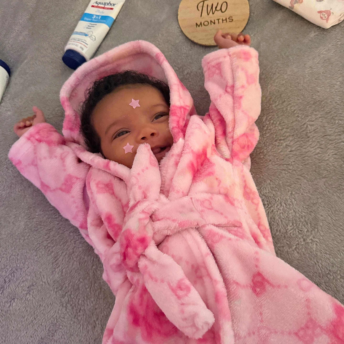 Jazaria joined the competition — help win amazing prizes! baby, infant, child, smiling, portrait, pink_blanket, robe, hood, lying_down, cozy, milestone_card, two_months, wooden_sign, gray_blanket, skincare_product, pouch, star_stickers, raised_arms, indoor, happy