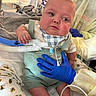 baby, child, medical_equipment, hospital, gloves, tubes, bib, overalls, bed, blanket, person, healthcare, infant, support, hand, medical_care, cute, indoor, patient, care