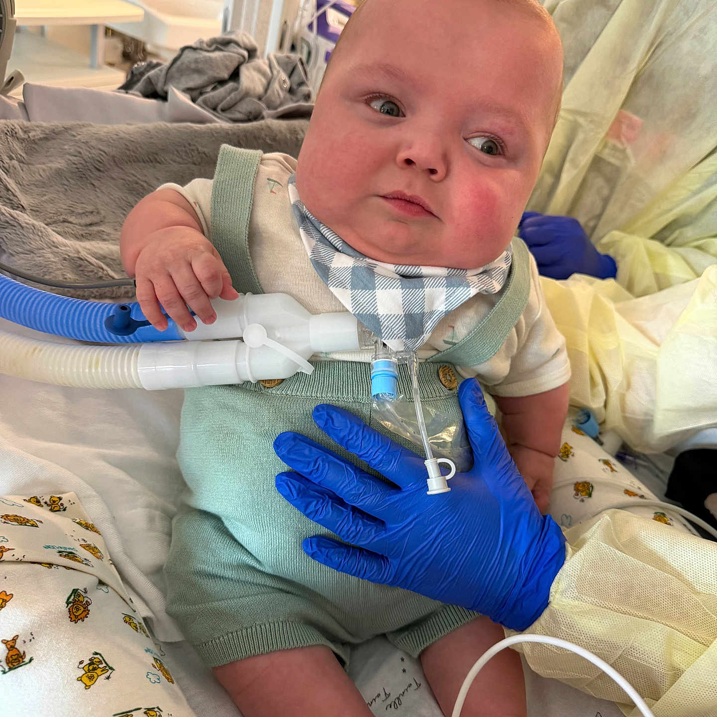 Zander joined the competition — help win amazing prizes! baby, child, medical_equipment, hospital, gloves, tubes, bib, overalls, bed, blanket, person, healthcare, infant, support, hand, medical_care, cute, indoor, patient, care
