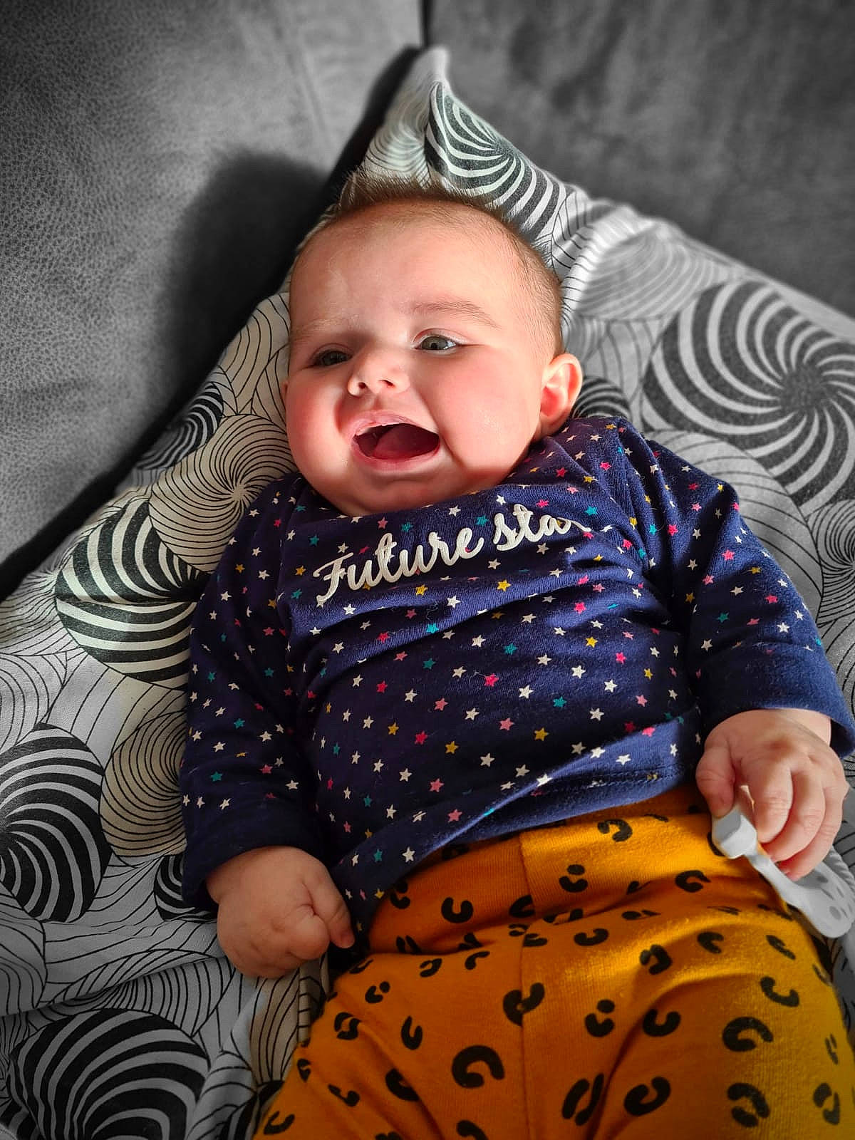 Maïna participe au concours pour gagner de l'argent avec cette photo : baby, baby_laughing, baby_products, baby_toddler_clothing, cheek, child, comfort, costume_accessory, couch, hair_accessory, human_body, living_room, mammal, mouth, nose, pattern, person, polka_dot, toddler, tongue