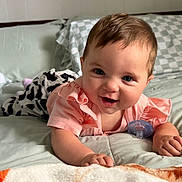 Mckenna is registered to the contest to win money with this photo: baby, bed, bedding, bedroom, blanket, blue_eyes, brown_hair, child, cozy, happy, indoors, infant, pacifier, photography, pillow, pink_clothing, plush_toy, portrait, sitting, smiling