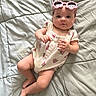 baby, child, infant, onesie, strawberry_pattern, pink_sunglasses, flower_shaped_sunglasses, blanket, bed, soft_texture, cute, lying_down, portrait, human, baby_clothing, indoor, skin, face, headwear, relaxed