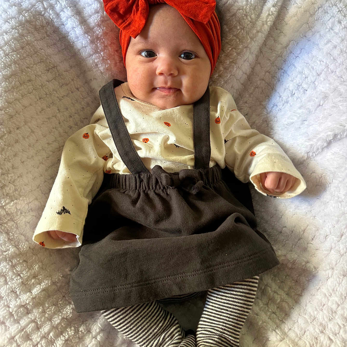Neilani joined the competition — help win amazing prizes! baby, blanket, child, cozy, cute, headwear, indoors, infant, lying_down, orange_bow, person, portrait, pumpkin_prints, skirt, smiling, soft_texture, striped_socks, suspenders, sweater, white_blanket