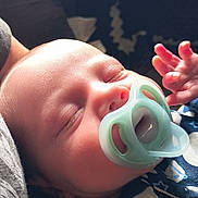 Noah is registered to the contest to win money with this photo: baby, sleeping, pacifier, infant, closeup, hand, face, peaceful, cozy, clothing, pattern, soft_light, cute, newborn, rest, child, portrait, indoor, skin, peace