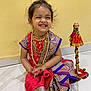 Meera joined the competition — help win amazing prizes! child, girl, smile, traditional_clothing, saree, jewelry, necklaces, floor, indoor, decorative_item, yellow_wall, happy, cultural, portrait, sitting, barefoot, cute, celebration, festive, accessories