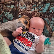Christain Musick joined the competition — help win amazing prizes! baby, dog, blanket, camo_pattern, bed, pacifier, infant, pet, snuggling, comfort, cute, animal, child, laying_down, clothing, indoor, friendship, affection, portrait, relaxation