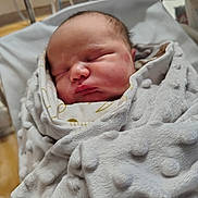 Aivar is registered to the contest to win money with this photo: newborn, baby, sleeping, blanket, hospital, bassinet, soft_texture, wrapped, infant, peaceful, face, head, indoors, closeup, person, cute, resting, newborn_baby, child, warm