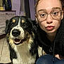 Shadow participe au concours pour gagner de l'argent avec cette photo : dog, woman, glasses, indoor, smiling_dog, face, person, floor, tile_floor, black_clothing, fur, happy, cute, portrait, pet, living_room, home_decor, cabinet, playful, closeup