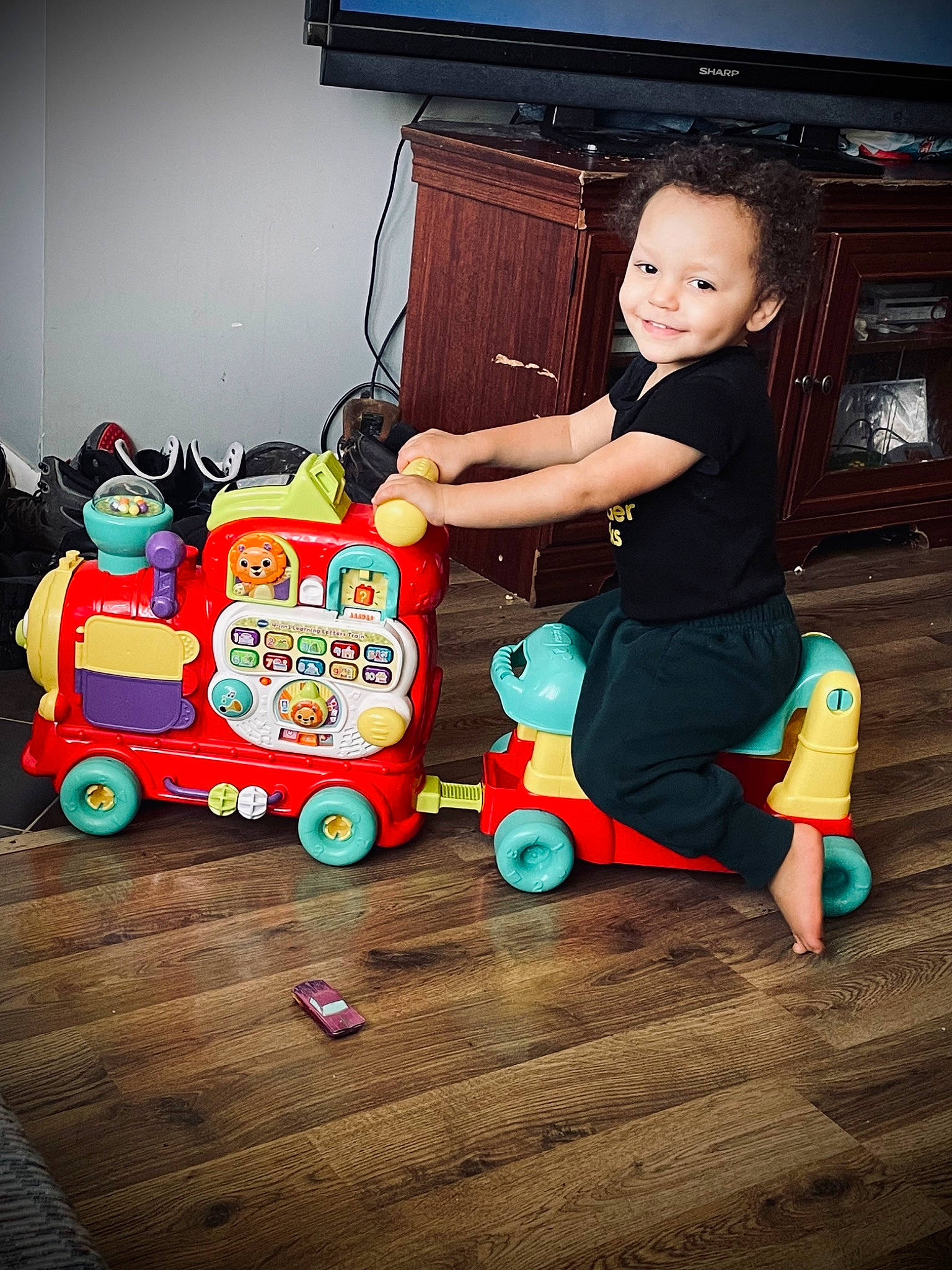Oliver joined the competition — help win amazing prizes! baby, child, flash_photography, floor, flooring, fun, happy, hardwood, joy, machine, person, play, room, sitting, t_shirt, television, tire, toddler, toy, toy_vehicle
