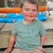 Brantlee is registered to the contest to win money with this photo: toddler, child, smiling, green_shirt, shorts, outdoor, wooden_steps, inflatable_pool, summer, happy, face, portrait, casual_clothing, blush, playful, daylight, skin, hair, person, sitting