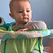 Charles joined the competition — help win amazing prizes! baby, child, infant, baby_seat, green, teal, gray_clothing, blue_wall, poster, cartoon, indoor, soft_light, cute, sitting, portrait, young_child, curious, face, hands, legs