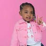 child, girl, pink_jacket, denim_skirt, braided_hair, beads, peace_sign, smiling, portrait, studio, colorful, fashion, cute, happy, pink_background, toddler, casual_clothing, posing, young_child, playful