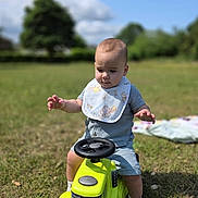 Roman joined the competition — help win amazing prizes! baby, child, toy, tractor, outdoor, grass, bib, blue_sky, greenery, sunlight, socks, playing, cute, infant, one_person, summer, nature, daytime, portrait, happy