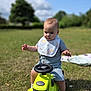 baby, child, toy, tractor, outdoor, grass, bib, blue_sky, greenery, sunlight, socks, playing, cute, infant, one_person, summer, nature, daytime, portrait, happy