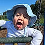 baby, child, swing, playground, hat, blue_sky, sunhat, white_shirt, happy, smiling, outdoor, daylight, fence, wood_chips, metal_chain, greenery, cute, infant, joyful, person