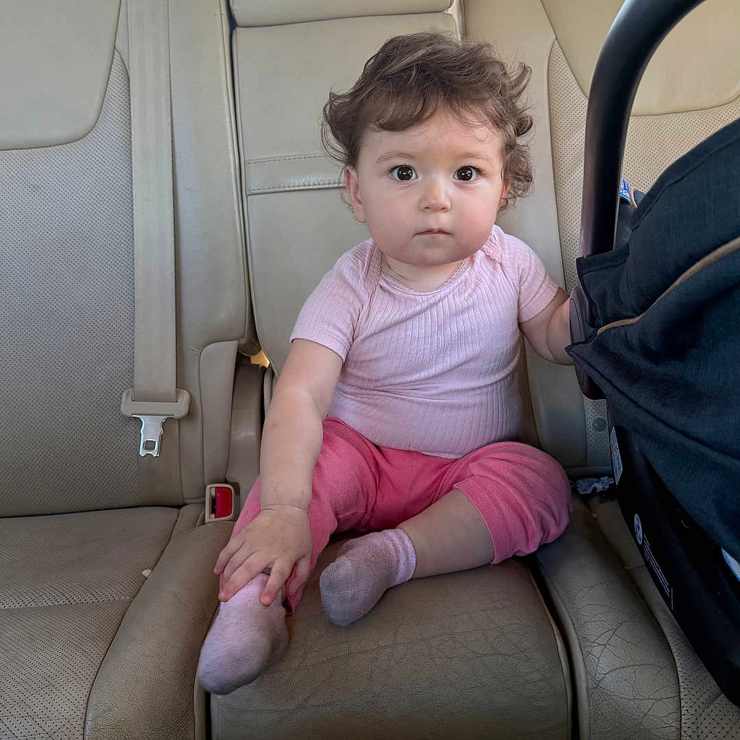 Yasmina joined the competition — help win amazing prizes! baby, backseat, car_interior, car_seat, casual, child, curious_expression, cute, daylight, headrest, indoor, infant, leather_seat, person, pink_clothing, portrait, seatbelt, socks, vehicle, window