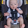 baby, bare_feet, car_seat, child, facial_expression, feet, grass, gray_clothing, hands, harness, headrest, indoors_outdoors, infant, photography, portrait, safety, sitting, vehicle_equipment, warning_label, wide_eyed