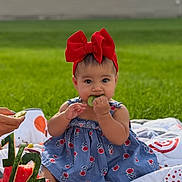 Giselle joined the competition — help win amazing prizes! baby, blanket, blue_dress, celebration, child, cute, food, fruit, girl, grass, happy, kiwi, nature, outdoor, portrait, red_bow, sitting, snack, summer, watermelon_cake