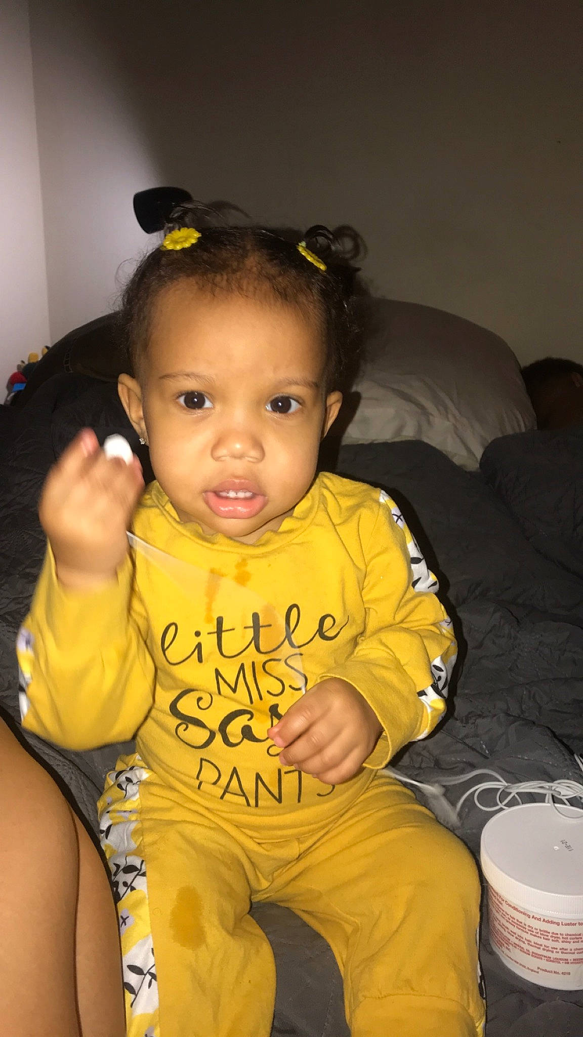 Lailah is registered to the contest to win money with this photo: baby, black_hair, cheek, child, ear, face, hairstyle, head, lip, person, sitting, skin, smile, toddler, yellow