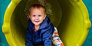 James is registered to the contest to win money with this photo: toddler, child, playground, slide, yellow, blue_hoodie, colorful_pants, smiling, crawling, happy, outdoor, fun, play, clothing, sock, young_child, cute, active, recreation, person