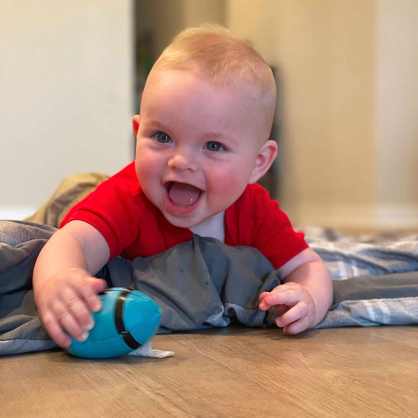 Lucas is registered to the contest to win money with this photo: baby, ball, bodypart, clothing, face, finger, football, hand, happy, hardwood, head, laughing, pants, person, photography, portrait, sitting, soccer, soccerball, sport