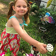 Kyah is registered to the contest to win money with this photo: backyard, butterfly_decor, child, dress, flowers, garden, girl, grass, greenery, hand, happy, metal_garden_decor, outdoor_play, pigtails, plant, playful, portrait, smiling, summer, watering_can