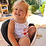 child, smiling, high_chair, bread, crumbs, outdoor, sunlight, garden, greenery, happy, casual_clothing, summer, toddler, cute, playful, seat, person, daylight, skin, hair