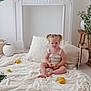 toddler, child, blonde_hair, pigtails, sitting, blanket, lemons, white, lace, cushion, decor, plant, pottery, wooden_stool, hat, neutral_colors, indoor, floor, curious, cozy