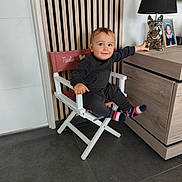 Matéïs participe au concours pour gagner de l'argent avec cette photo : toddler, child, chair, indoor, lamp, dresser, wood_panel, floor, socks, clothing, portrait, smile, furniture, person, baby, toy, decor, photograph, modern, home