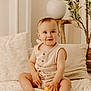 Matéïs participe au concours pour gagner de l'argent avec cette photo : toddler, child, baby, indoor, sitting, blanket, pillows, lemons, neutral_colors, smiling, cute, decor, plant, wooden_table, cozy, soft_light, portrait, furniture, home, casual_clothing