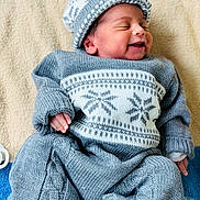 Parthiv a rejoint le concours — aidez-le/la à gagner de superbes lots ! baby, newborn, smiling, knitwear, hat, blue_clothing, blanket, sleeping_baby, infant, cute, cozy, soft_texture, portrait, child, resting, indoors, warm, small_hands, buttoned_pants, happy