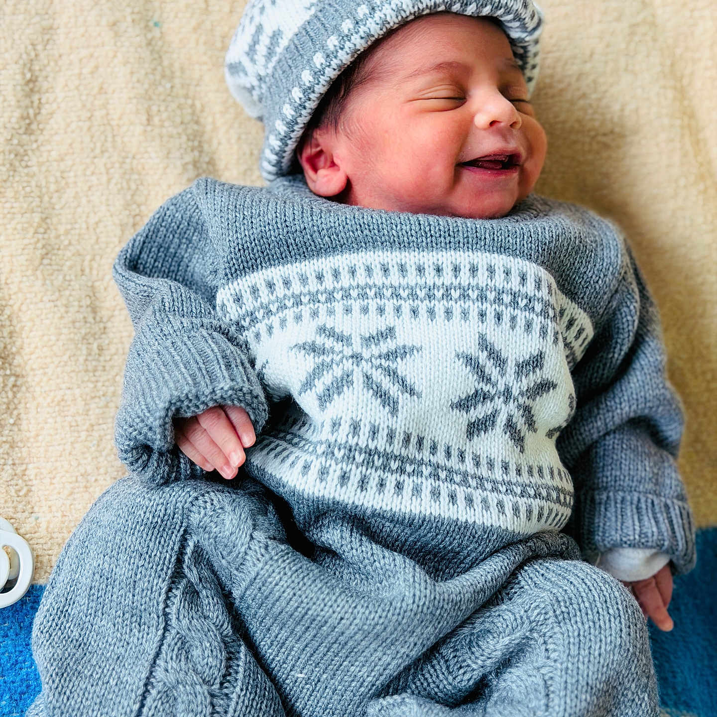 Parthiv a rejoint le concours — aidez-le/la à gagner de superbes lots ! baby, newborn, smiling, knitwear, hat, blue_clothing, blanket, sleeping_baby, infant, cute, cozy, soft_texture, portrait, child, resting, indoors, warm, small_hands, buttoned_pants, happy