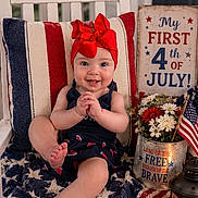 Jacey joined the competition — help win amazing prizes! baby, child, red_bow, chair, american_flag, blanket, flowers, lantern, patriotic, celebration, holiday, decorations, sign, smile, indoors, portrait, cute, festive, fourth_of_july, happy
