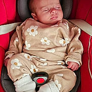 Tess participe au concours pour gagner de l'argent avec cette photo : baby, sleeping, car_seat, red, beige, flower_pattern, clothing, white_socks, infant, child, cute, peaceful, seatbelt, head_support, portrait, indoors, soft_lighting, small_hands, cozy, resting
