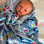 baby, infant, blanket, blue, dinosaur_pattern, wrapped, newborn, face, eyes, soft, bed, resting, cute, child, portrait, warm, cozy, clothing, lying, fabric