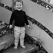 Juliano participe au concours pour gagner de l'argent avec cette photo : toddler, child, barefoot, stairs, metal_stairs, smiling, boy, long_sleeve_shirt, pants, outdoor, leaves, plants, black_and_white, portrait, happy, standing, face, hair, railing, nature