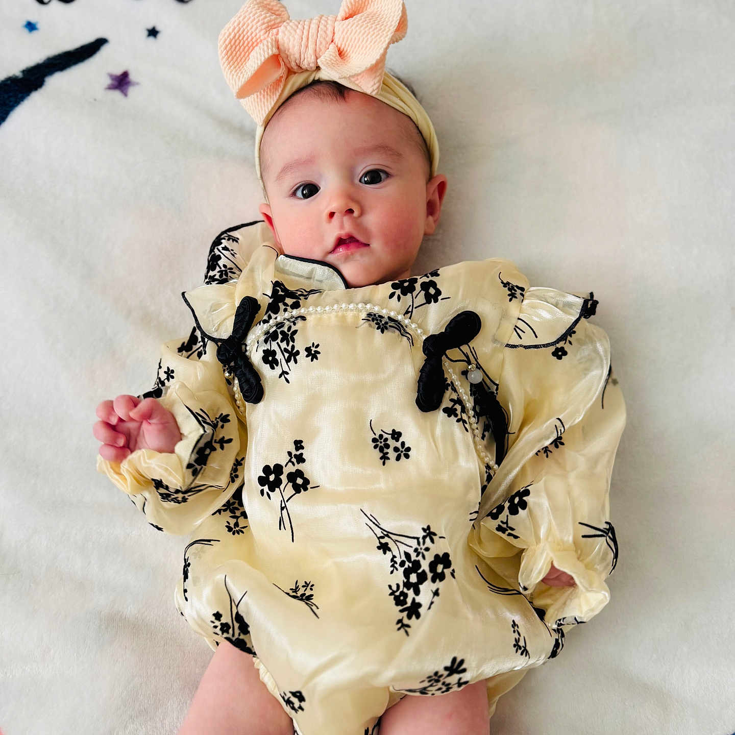 Athena is registered to the contest to win money with this photo: baby, bodypart, bonnet, cap, clothing, dress, face, finger, flower, formalwear, hand, hat, head, newborn, person, photography, portrait, sitting, sleeve, toy