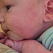 Zoey joined the competition — help win amazing prizes! baby, infant, newborn, face, cheek, ear, eye, hand, fingers, onesie, sleeve, skin, portrait, close_up, lying_down, cuddling, bedding, blanket, palm, watermark