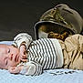 Liam a rejoint le concours — aidez-le/la à gagner de superbes lots ! baby, infant, striped_clothing, pants, blanket, helmet, reflective_surface, lying_down, soft_texture, cute, cozy, sleepy, portrait, baby_clothes, indoor, headwear, small_hands, resting, toddler, child