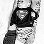 baby, superman, sweater, tattoo, arm, hand, infant, clothing, pants, foot, black_and_white, portrait, lying_down, person, cute, newborn, soft_texture, fabric, casual_wear, relaxing